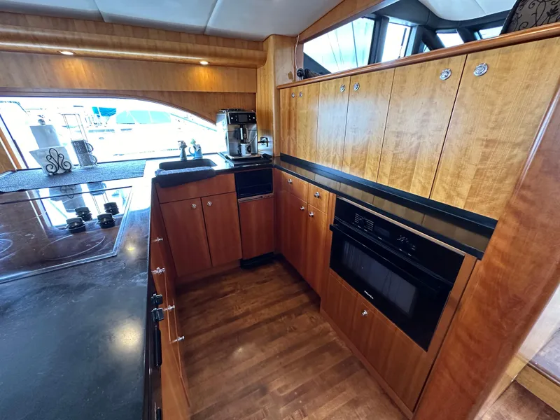 Slide: The Image of 1999 Queenship Cockpit Motoryacht kitchen with wooden cabinets and modern appliances. - 10