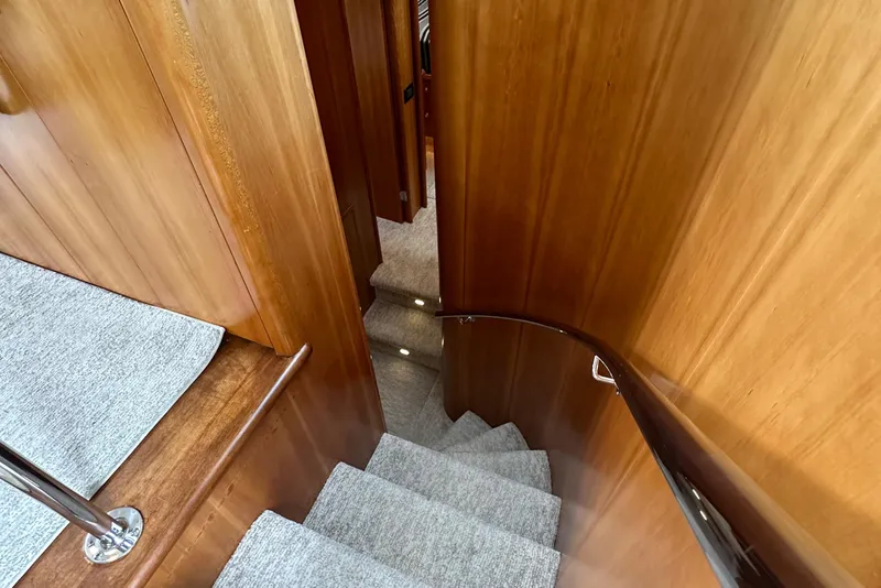 Slide: The Image of Staircase inside 1999 Queenship Cockpit Motoryacht with wooden paneling and carpeted steps. - 18