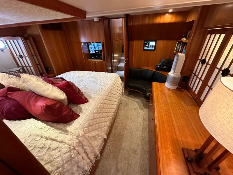 Slide: The Image of Luxurious bedroom interior of a 1999 Queenship Cockpit Motoryacht with wooden furnishings and cozy bedding. - 25