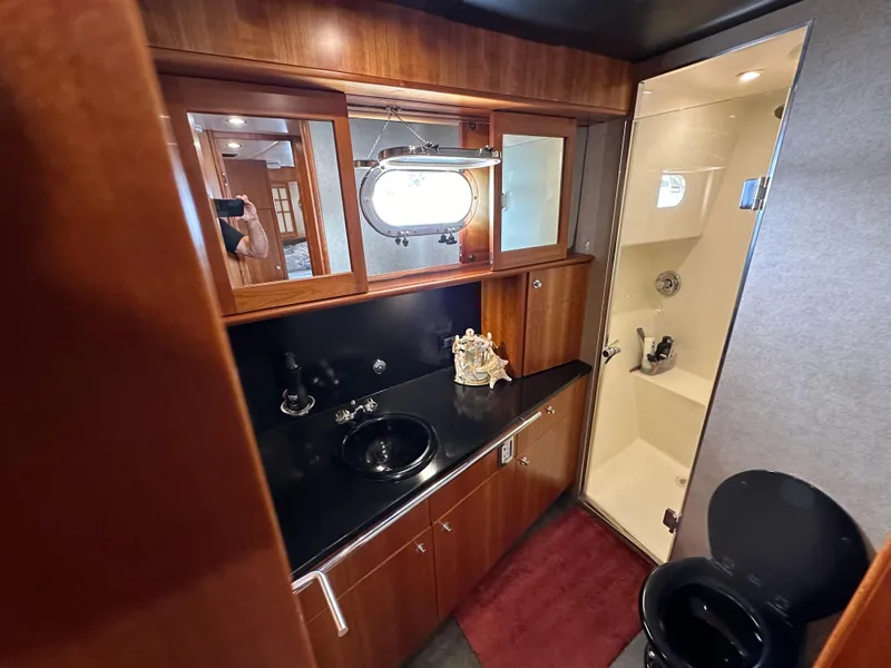 Slide: The Image of 1999 Queenship Cockpit Motoryacht bathroom with black sink, wooden cabinets, and shower. - 27