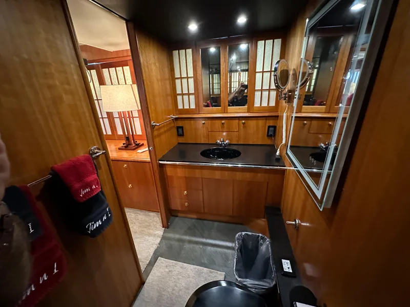Slide: The Image of 1999 Queenship Cockpit Motoryacht bathroom with wooden cabinetry and black countertop. - 29