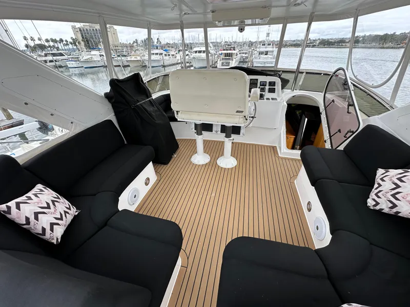 Slide: The Image of 1999 Queenship Cockpit Motoryacht interior with black seating, helm station, and marina view. - 34