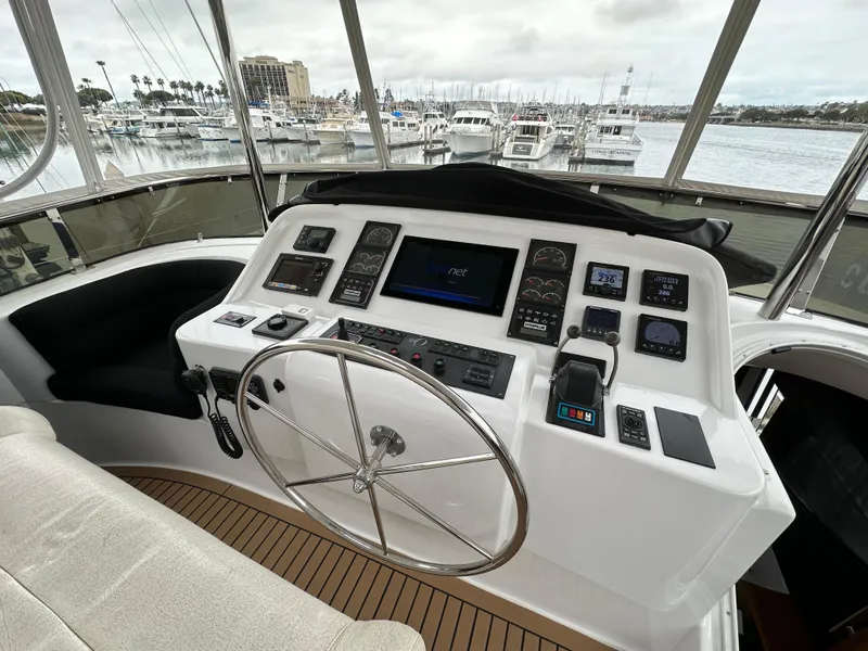 Slide: The Image of 1999 Queenship Cockpit Motoryacht helm with modern navigation instruments and panoramic marina view. - 35