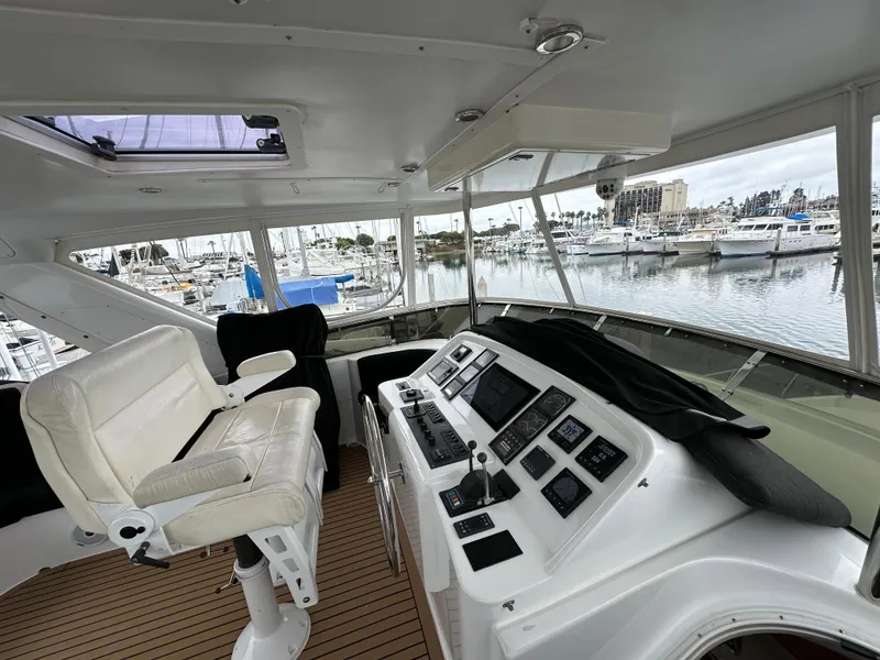 Slide: The Image of 1999 Queenship Cockpit Motoryacht helm station with marina view. - 36