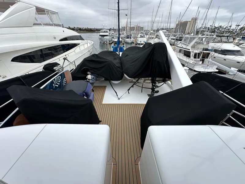 Slide: The Image of 1999 Queenship Cockpit Motoryacht docked at a marina, covered equipment on deck. - 38