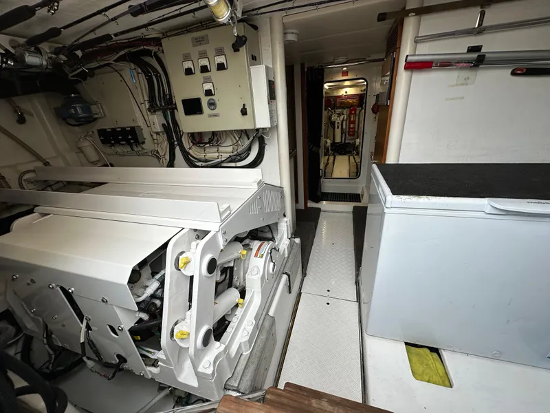 Slide: The Image of Engine room of a 1999 Queenship Cockpit Motoryacht with visible machinery and control panels. - 47