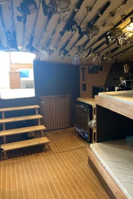 Slide: The Image of 2022 Custom Carolina Sportfish interior with fishing rods, wooden stairs, and bunks. - 17