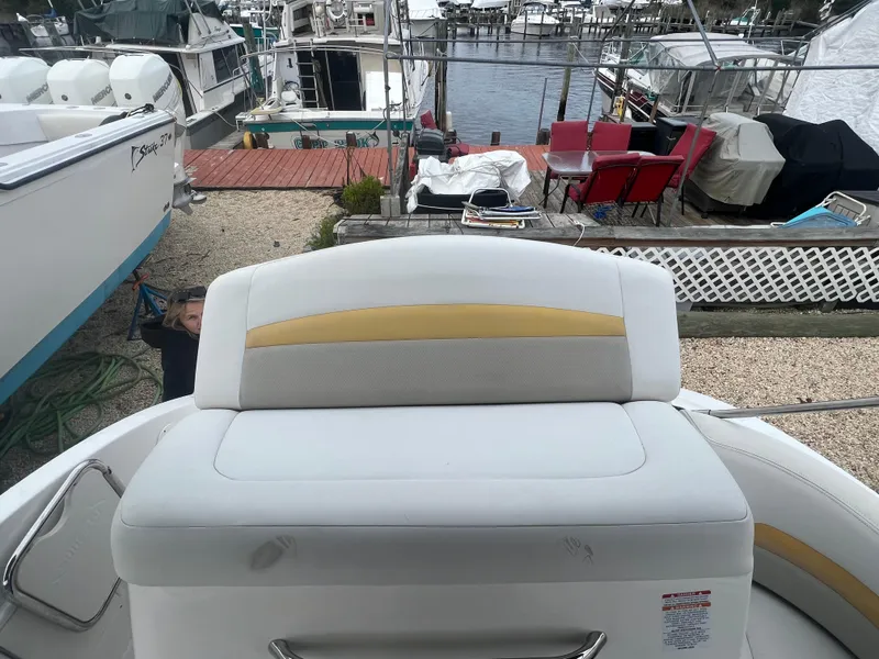 Slide: The Image of 2012 Chaparral 264 Sunesta boat interior with white and yellow seating at a marina. - 11