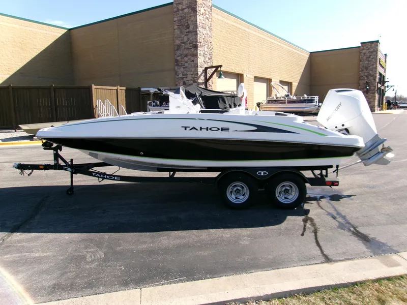 Slide: The Image of 2024 Tahoe 2150 CC boat on trailer, parked outdoors near a building. - 2