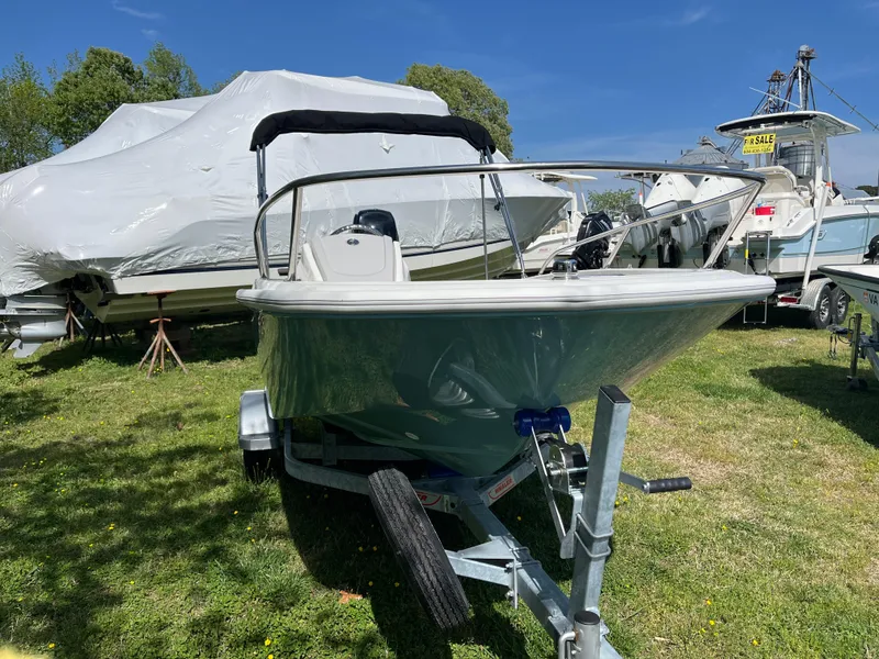 Slide: The Image of 2025 Boston Whaler 130 Super Sport boat on trailer, parked on grass under clear blue sky. - 19