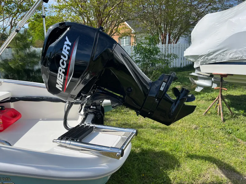 Slide: The Image of Boston Whaler 130 Super Sport 2025 with Mercury outboard motor in a grassy yard. - 2