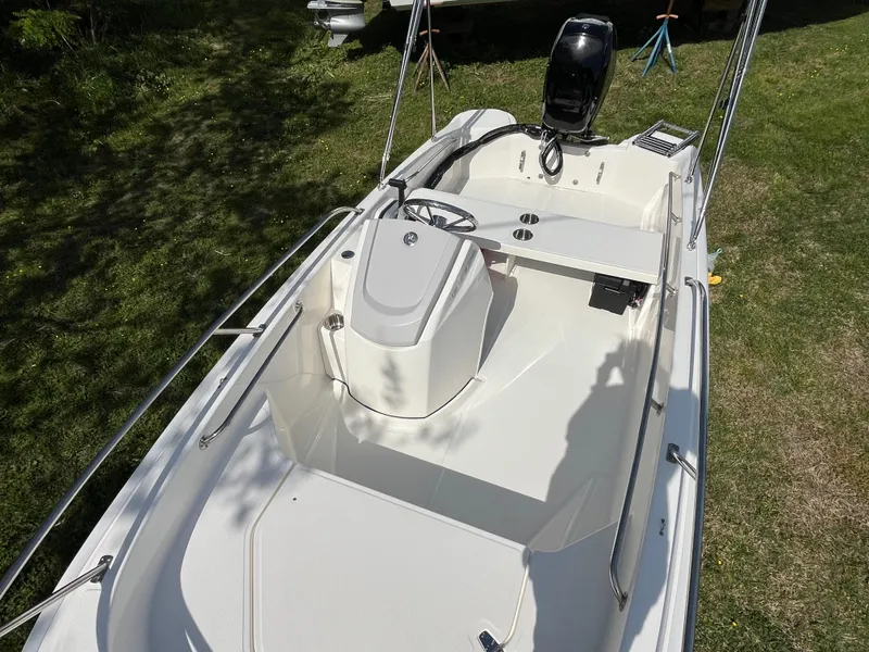 Slide: The Image of 2025 Boston Whaler 130 Super Sport boat, white interior, parked on grass. - 3