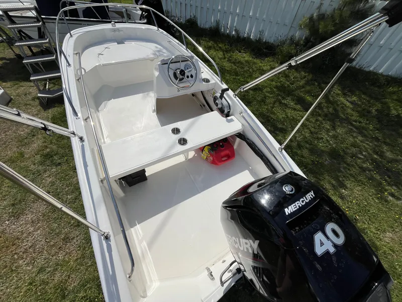Slide: The Image of 2025 Boston Whaler 130 Super Sport boat with Mercury 40 engine, parked on grass. - 4