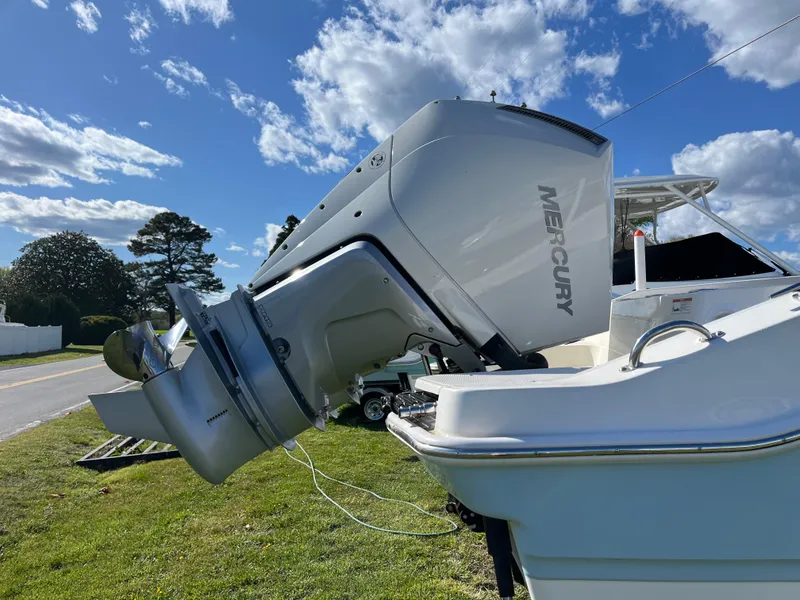 Slide: The Image of 2025 Boston Whaler 280 Dauntless with Mercury outboard engine, parked on grass under blue sky. - 2