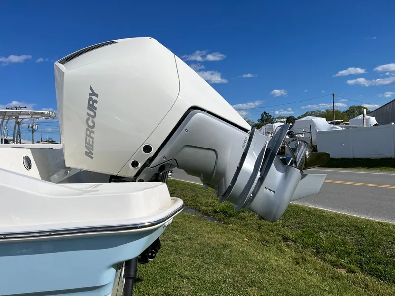 Slide: The Image of 2025 Boston Whaler 280 Dauntless with Mercury outboard engine, parked on grass under blue sky. - 32