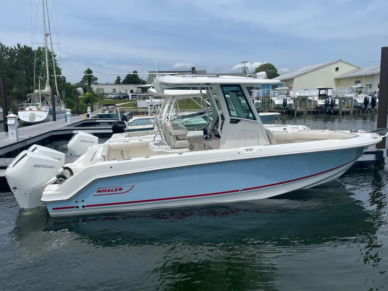 The Image of 2025 Boston Whaler 250 Outrage boat docked in a marina, featuring sleek design and twin engines. - 0