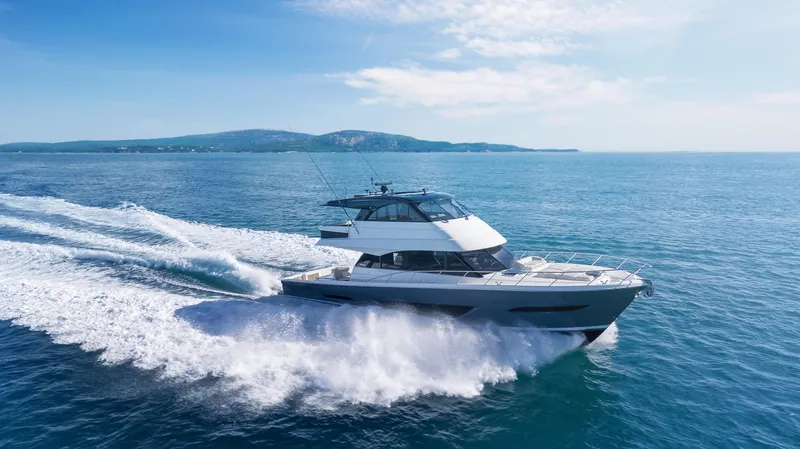 Slide: The Image of 2026 Maritimo M600 yacht cruising on open sea with scenic coastline in background. - 2