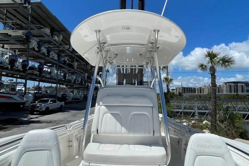 Slide: The Image of 2017 Regulator R23 boat with white seating and T-top in a marina. - 11