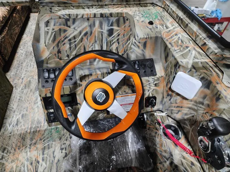 Slide: The Image of 2024 SeaArk EasyCat boat dashboard with camo design and orange steering wheel. - 3