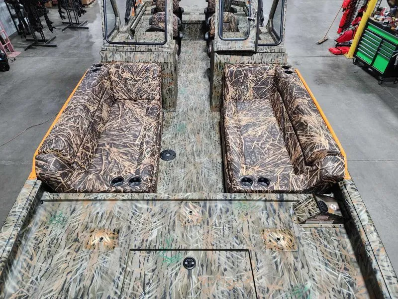 Slide: The Image of 2024 SeaArk EasyCat boat interior with camo seating and flooring in a workshop. - 6