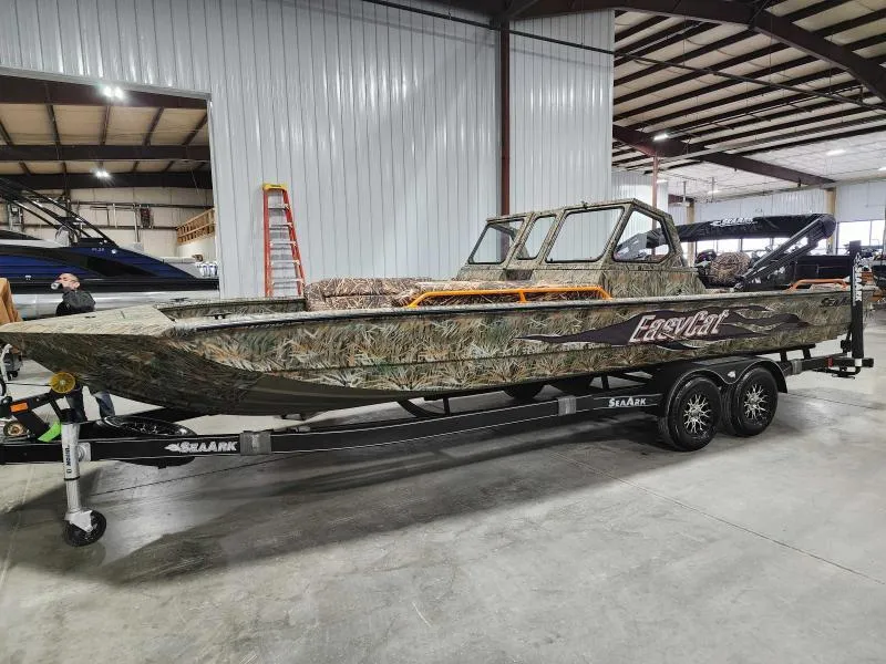 Slide: The Image of 2024 SeaArk EasyCat boat in camouflage design on a trailer inside a warehouse. - 7