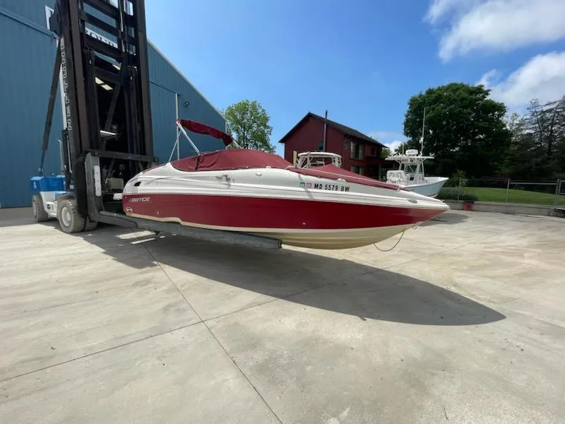 The Image of 2005 Chaparral 2300 boat in red and white, lifted by a forklift. - 0