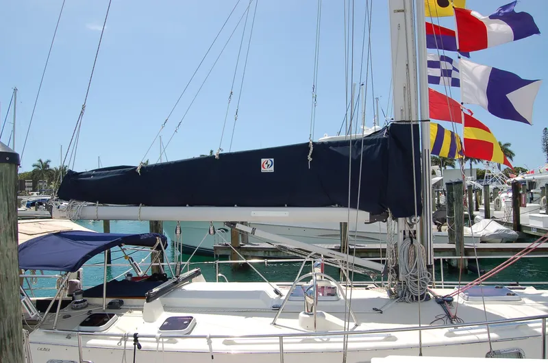 Slide: The Image of 2005 Caliber 40 LRC SE sailboat docked, featuring colorful signal flags and a covered boom. - 16