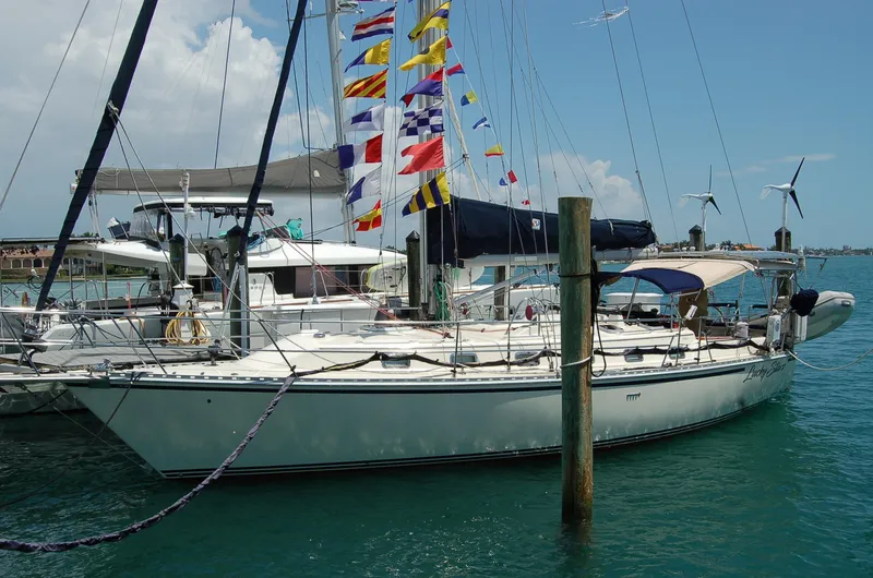 Slide: The Image of 2005 Caliber 40 LRC SE sailboat docked, adorned with colorful flags, in a sunny marina. - 2