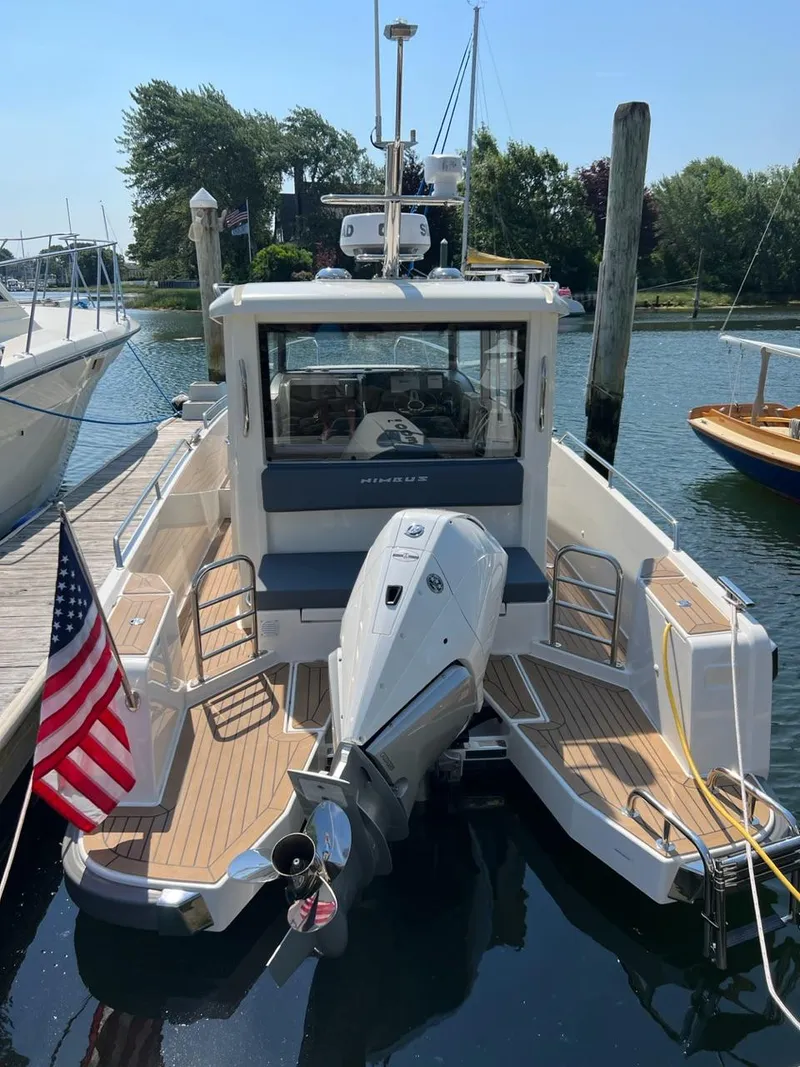 Slide: The Image of 2023 Nimbus C9 boat docked, rear view with American flag and outboard motor. - 2