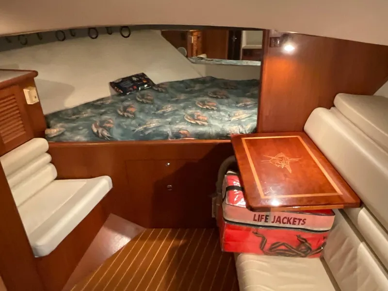 Slide: The Image of 1999 Pursuit Offshore Express cabin interior with seating, table, and life jackets. - 14