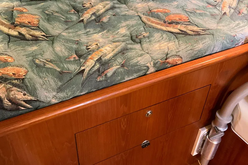 Slide: The Image of 1999 Pursuit OFFSHORE EXPRESS interior with fish-patterned upholstery and wooden cabinetry. - 17