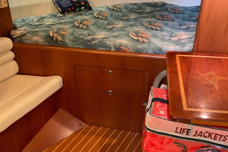 Slide: The Image of 1999 Pursuit Offshore Express cabin with bed, wooden interior, and life jackets. - 18