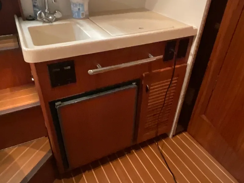 Slide: The Image of 1999 Pursuit Offshore Express boat interior with sink and wooden cabinetry. - 19