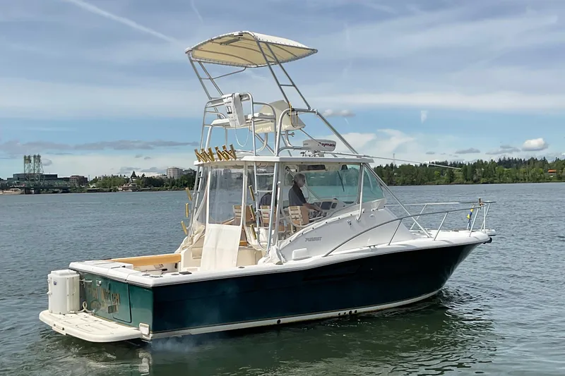 Slide: The Image of 1999 Pursuit Offshore Express boat on calm water, featuring a tower and canopy. - 2