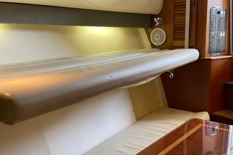 Slide: The Image of 1999 Pursuit Offshore Express interior with cushioned seating and wooden accents. - 22