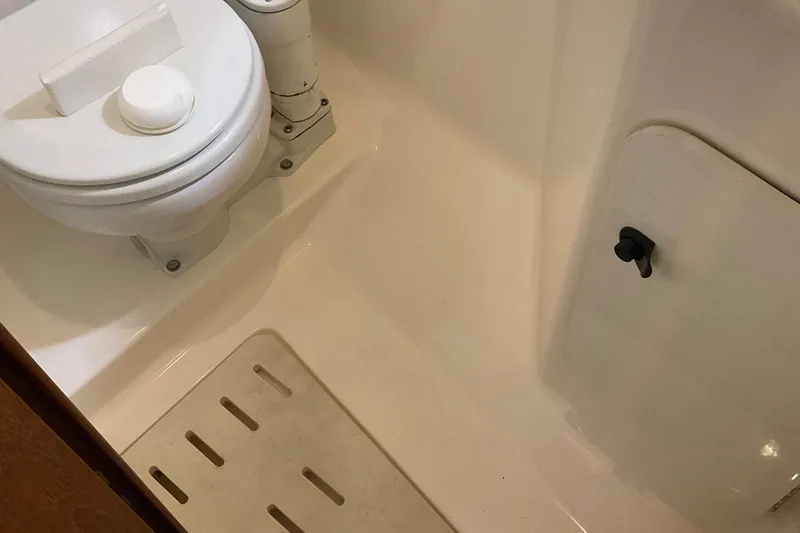 Slide: The Image of 1999 Pursuit Offshore Express boat bathroom with toilet and shower area. - 23