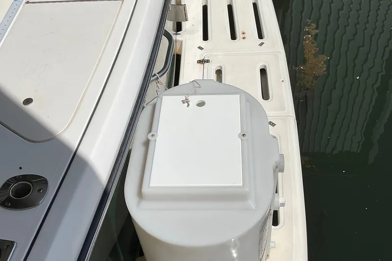 Slide: The Image of 1999 Pursuit Offshore Express boat deck with storage compartment by the water. - 38