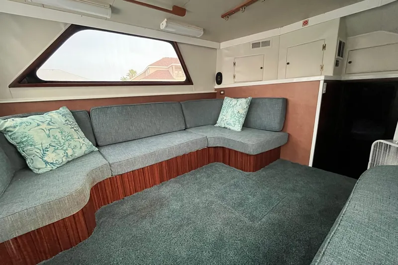 Slide: The Image of Interior of a 1972 Hatteras 42 Convertible yacht with grey seating and teal cushions. - 17