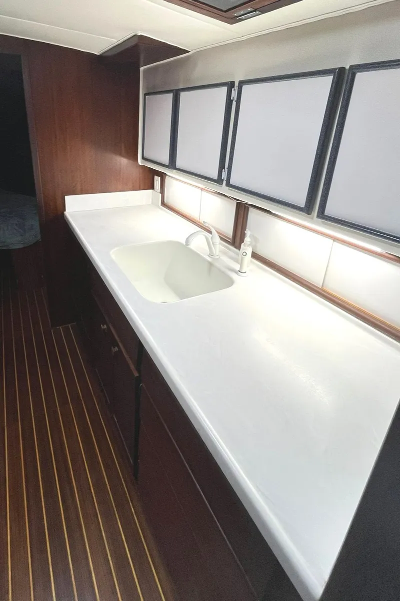 Slide: The Image of 1972 Hatteras 42 Convertible yacht kitchen with white countertop and wooden cabinets. - 19