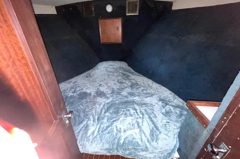 Slide: The Image of 1972 Hatteras 42 Convertible boat cabin with bed and wooden accents. - 24