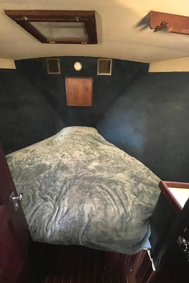 Slide: The Image of 1972 Hatteras 42 Convertible boat cabin with bed and wooden accents. - 25