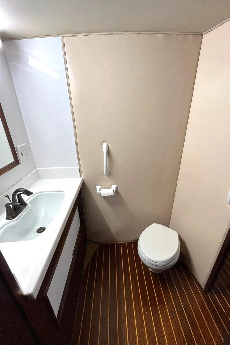 Slide: The Image of 1972 Hatteras 42 Convertible boat bathroom with sink, toilet, and wood flooring. - 27