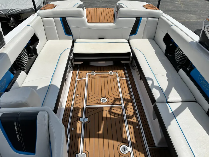 Slide: The Image of 2014 Nautique G25 boat interior with white seating and teak flooring. - 10