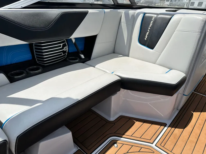 Slide: The Image of 2014 Nautique G25 boat interior with white and black seating, wood flooring. - 6