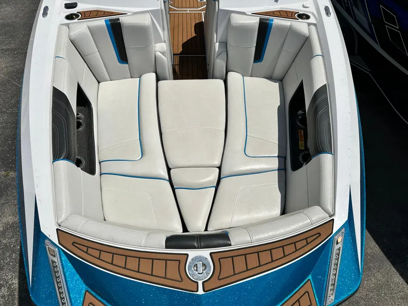Slide: The Image of 2014 Nautique G25 boat interior with white and blue cushioned seating. - 9