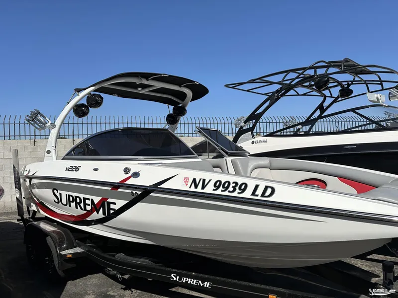 Slide: The Image of 2013 Supreme V226 boat with sleek design and custom graphics, parked on a trailer. - 12