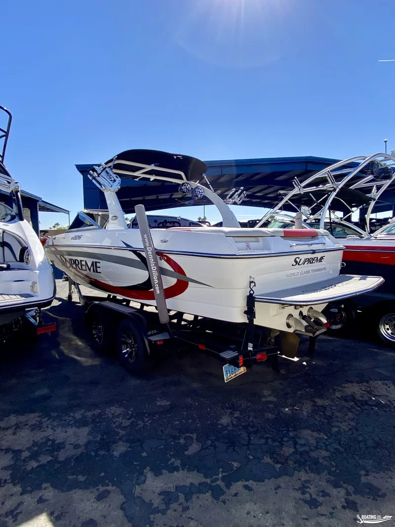Slide: The Image of 2013 Supreme V226 boat on trailer, parked outdoors under clear sky. - 2