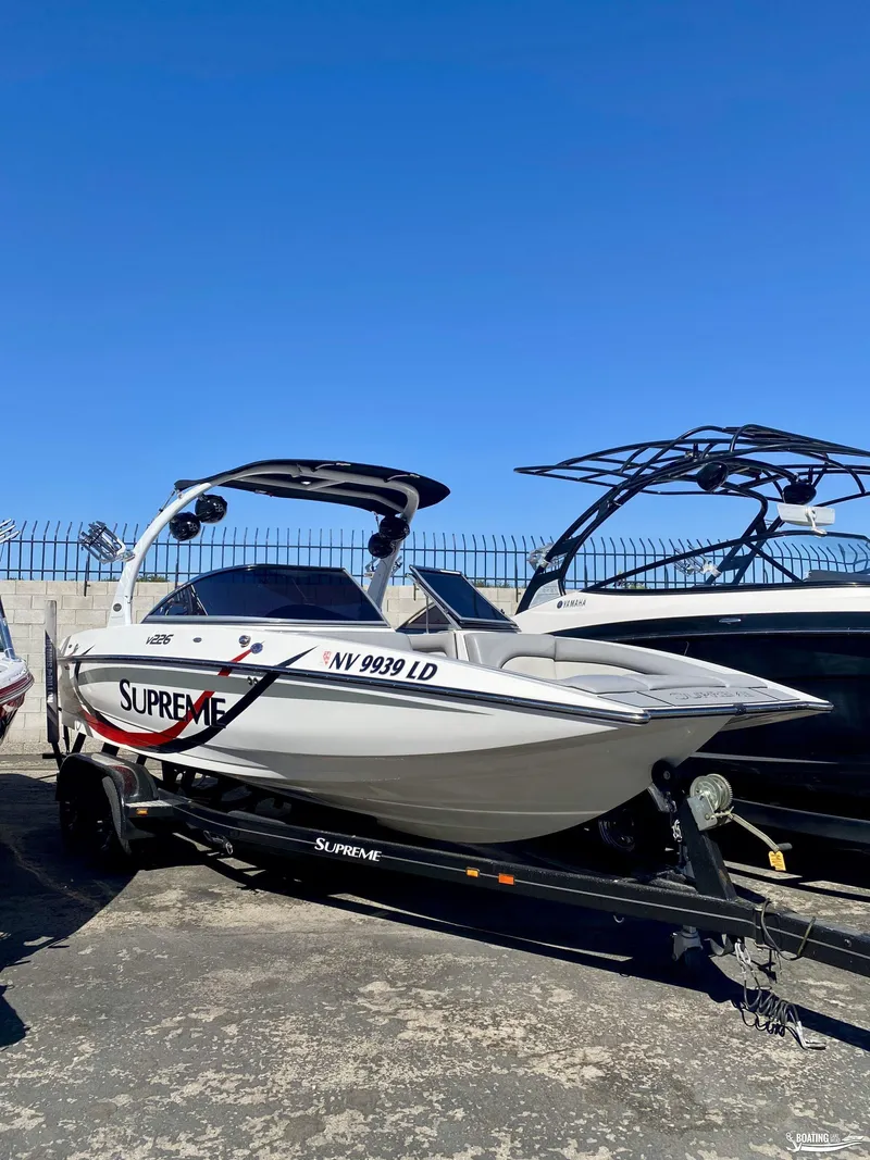 Slide: The Image of 2013 Supreme V226 boat on trailer under clear blue sky. - 4