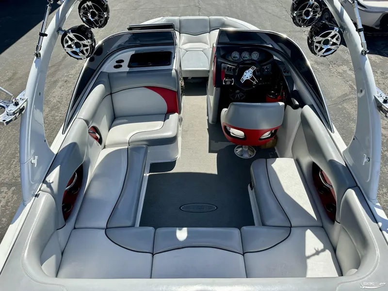 Slide: The Image of 2013 Supreme V226 boat interior with gray and red seating, steering console, and mounted speakers. - 8