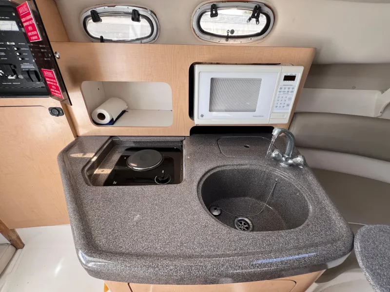 Slide: The Image of Compact kitchen area in a 2000 Boston Whaler 28 Conquest boat with sink, stove, and microwave. - 33